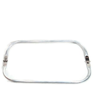 May include: A silver metal hoop with two hinges. The hoop is bent into a rectangular shape.