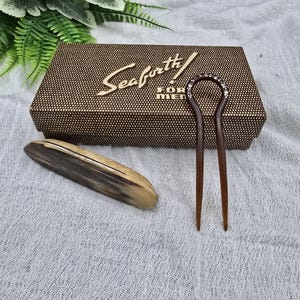 May include: A brown box with the text "Seaforth FOR MEN" is displayed. A wooden hair pin with a decorative top and a wooden comb are next to the box. The items are on a white textured surface.