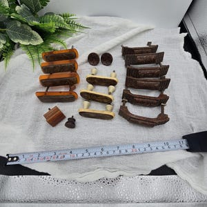 May include: A collection of vintage wooden furniture hardware, including drawer pulls and knobs, in shades of brown and tan. A measuring tape is included in the image. The hardware is arranged on a white cloth.