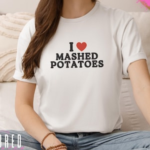 May include: White t-shirt with a red heart and the text "I love mashed potatoes" in black.