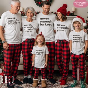 May include: A group of six people wearing matching white t-shirts and red and black plaid pajama pants. Each shirt has a different food-related phrase. The family is gathered in front of a decorated fireplace, creating a festive holiday scene.