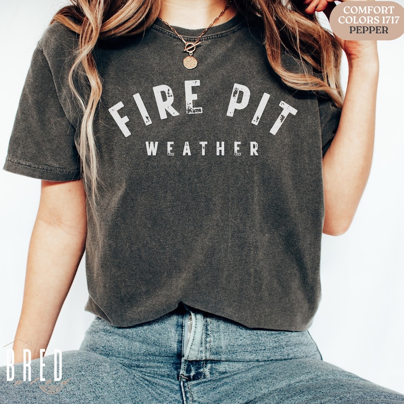 Fire Pit Weather shirt in Pepper Comfort Colors worn by a woman with jeans, styled for an effortless fall outdoor look.