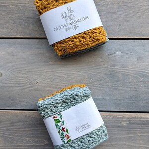 May include: Two crocheted washcloths, one mustard yellow and one light blue, with labels that say "Crochet Washcloth 100% Cotton" and "Handmade 100% New Cotton Wash before first use". The washcloths are on a gray wooden surface. SAVLABOT HANDMADE is written below the washcloths.