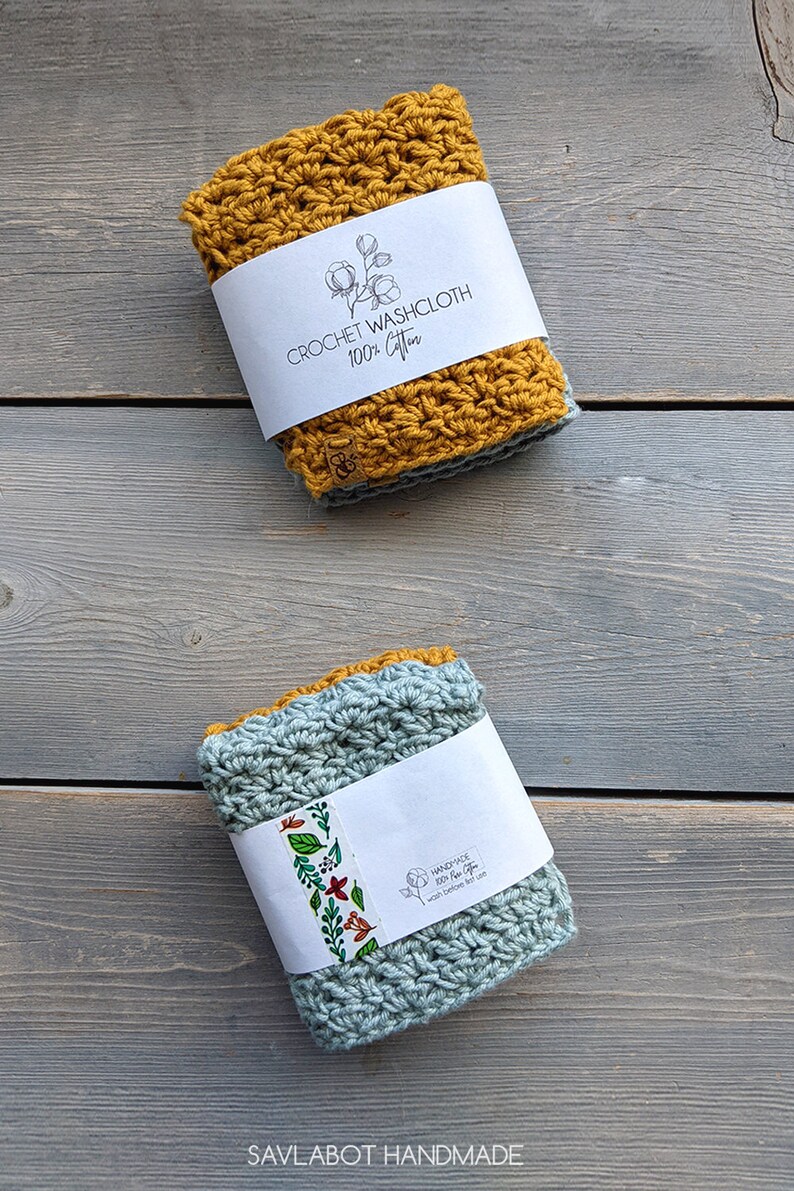 May include: Two crocheted washcloths, one mustard yellow and one light blue, with labels that say "Crochet Washcloth 100% Cotton" and "Handmade 100% New Cotton Wash before first use". The washcloths are on a gray wooden surface. SAVLABOT HANDMADE is written below the washcloths.