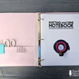 May include: A pink binder with a white cover sheet that says "Knitting Machine Notebook" with a black and red knitting machine illustration. The binder has a pocket on the left side with a blue sticky note, a pair of scissors, and a few gold clips.