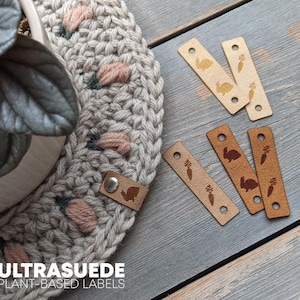 May include: Plant-based labels with rabbit and carrot designs. The labels are in shades of tan and brown, with pre-cut holes for sewing. The image also shows a knitted item with a plant in a white pot.