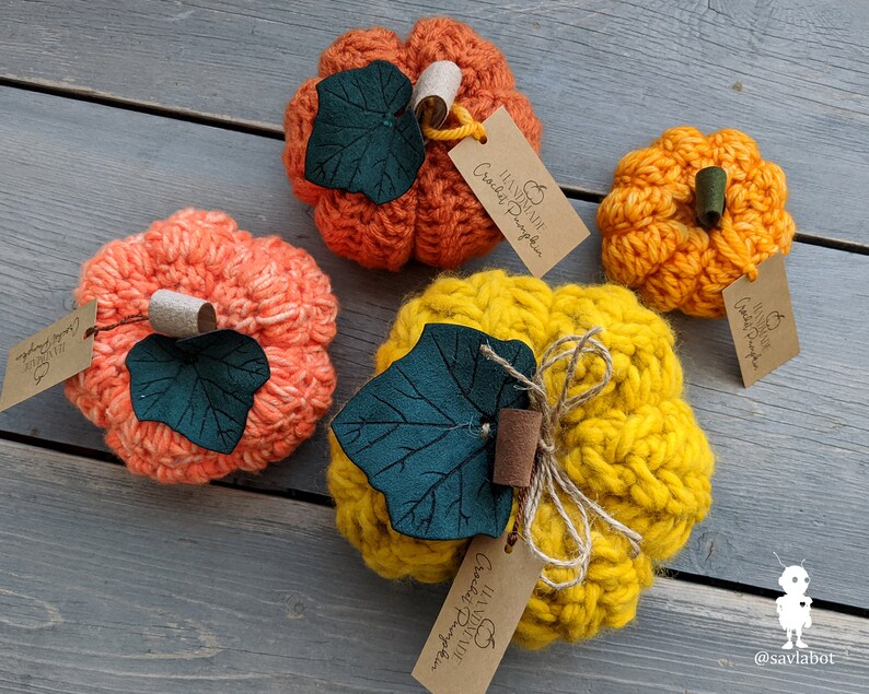 May include: Three crocheted pumpkins in orange, yellow, and peach colors with green felt leaves and brown twine. Each pumpkin has a small tag attached that says "Crochet Pumpkin".
