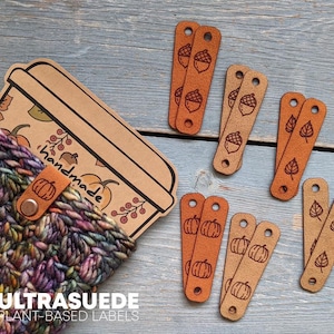May include: A multi-colored crocheted pouch with a tan tag labeled handmade, accompanied by several tan rectangular labels featuring engraved designs of acorns, pumpkins, and leaves, each with two small holes for attachment.