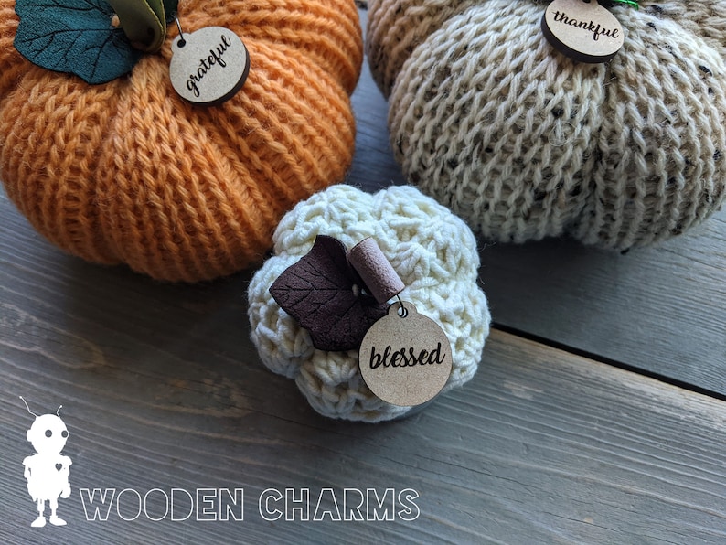 May include: Three knitted pumpkins with wooden tags that say "grateful", "thankful", and "blessed".