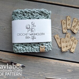 May include: A crocheted washcloth made of 100% cotton, with a label that reads "Crochet Washcloth 100% Cotton". The washcloth is light blue and has a floral design. There are also several small wooden tags with a floral design.