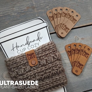 May include: A handmade cup cozy with the text "Handmade CUP COZY" and a leather tag that says "Coffee LOVE". The image also shows several brown tags with the words "Coffee LOVE" and "ULTRASUEDE PLANT-BASED LABELS".