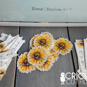May include: A close-up of a Cricut Explore Air 2 cutting machine with a variety of handmade sunflower-themed labels and tags. The labels feature the word "Handmade" and are ideal for adding a personal touch to gifts or crafts.
