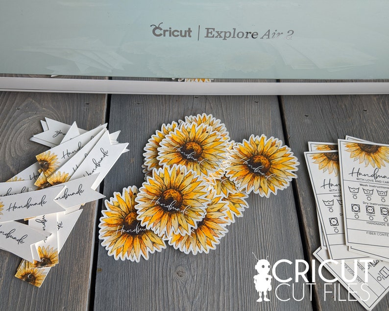 May include: A close-up of a Cricut Explore Air 2 cutting machine with a variety of handmade sunflower-themed labels and tags. The labels feature the word "Handmade" and are ideal for adding a personal touch to gifts or crafts.