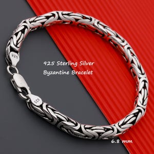 May include: A silver Byzantine bracelet with a 925 sterling silver stamp. The bracelet is 6.8 mm wide.