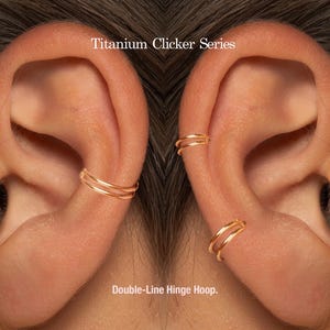 May include: Close-up of ears with gold double-line hinge hoop earrings. The earrings are part of the Titanium Clicker Series. The text "Double-Line Hinge Hoop" is at the bottom of the image.