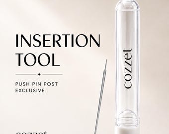 Könnte beinhalten: Ein dünnes Metalleinführwerkzeug für Push-Pin-Stifte, begleitet von einem transparenten zylindrischen Aufbewahrungsrohr mit weißem Boden. Das Rohr trägt den Markennamen cozzet und den Text INSERTION TOOL PUSH PIN POST EXCLUSIVE.