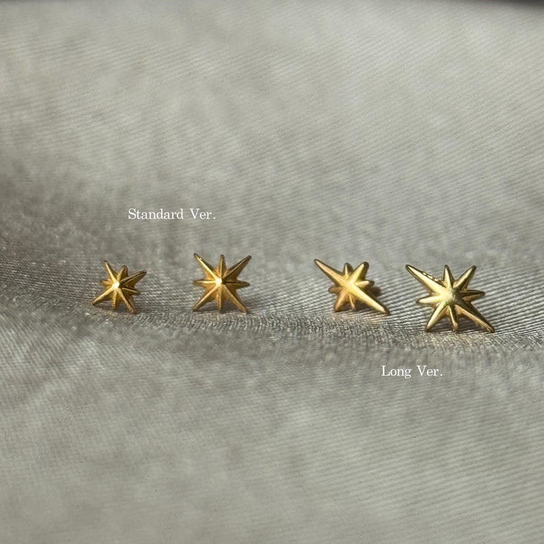 May include: Four gold-colored star-shaped earrings. Two pairs are labeled "Standard Ver." and "Long Ver." The earrings are displayed on a textured, light gray surface. The earrings have a shiny finish.