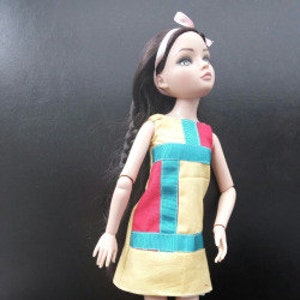 May include: A yellow, red, blue, and green patchwork dress for a doll. The dress has a sleeveless design and a straight neckline.