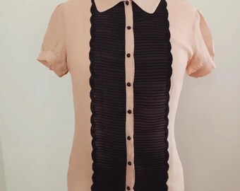 May include: A light pink short-sleeved blouse with a black lace overlay and a button-up front.