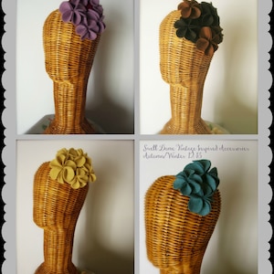 Puede incluir: Cuatro diademas de flores de fieltro en diferentes colores: morado, marr&oacute;n, amarillo y turquesa. Las diademas se muestran en cabezas de maniqu&iacute; con cuerpos de mimbre.