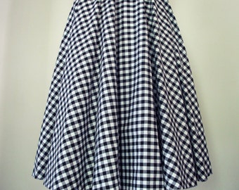May include: A black and white gingham dress with a full skirt. The dress is on a wooden dress form.