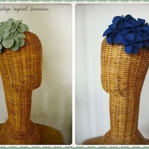 Puede incluir: Dos diademas de flores de fieltro, una de color verde claro y la otra de color azul oscuro. Las diademas se muestran en maniqu&iacute;es de mimbre.