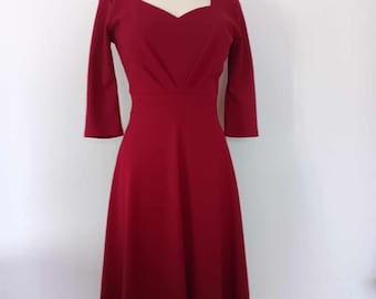 May include: A maroon midi dress with a sweetheart neckline and three-quarter sleeves. The dress has a fitted bodice and a flowing skirt.