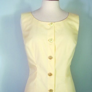 May include: A sleeveless yellow button-up top with a fitted waist.