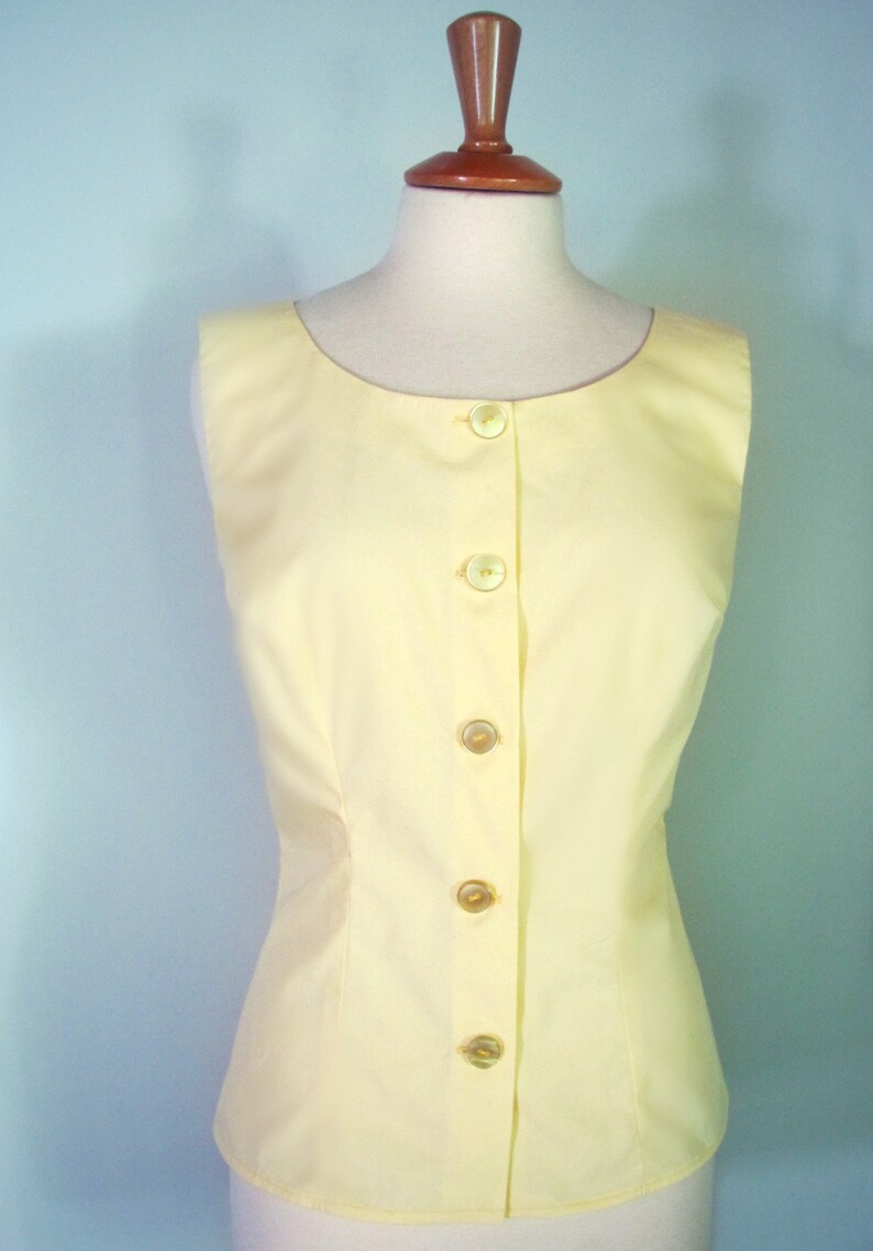 May include: A sleeveless yellow button-up top with a fitted waist.