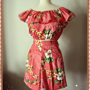 May include: A pink and green floral print two-piece outfit with a ruffled off-the-shoulder top and a high-waisted skirt. The outfit is on a mannequin and the brand name "Swell Dame Athens" is visible at the top of the image.