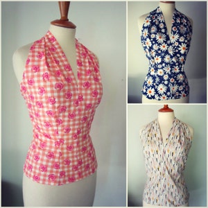 May include: Three halter tops with different floral patterns. The first top is pink and white gingham with pink flowers. The second top is navy blue with white daisy flowers. The third top is white with a multi-colored abstract pattern.