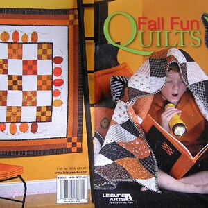 May include: A book titled "Fall Fun Quilts" with 8 unique projects to celebrate fall by Nan Slaughter. The book cover features a child reading under a quilt with a flashlight. The quilt is made of orange, black, and white fabric.