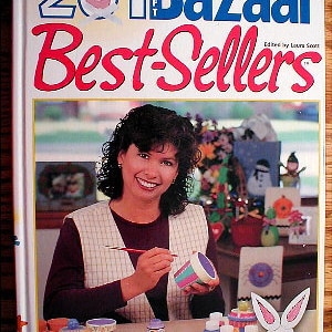 May include: A woman paints a ceramic container with a paintbrush. The container is decorated with a colorful design. The image is from a book titled "201 Bazaar Best-Sellers" edited by Laura Scott.