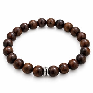 May include: A circular stretch bracelet composed of polished, dark brown spherical beads with a visible wood grain texture. A single cylindrical silver-toned metal spacer bead featuring an intricate, engraved geometric Greek key pattern is centred.