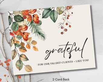 May include: A cream-colored card with the word "grateful" in elegant black script. The card is adorned with watercolor illustrations of autumn leaves in shades of orange, green, and brown. Text at the bottom reads "FOR OUR VALUED CLIENTS - LIKE YOU!"