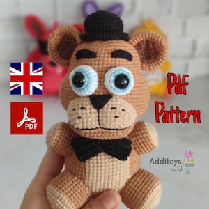 Puede incluir: Patrón de crochet para un oso marrón que lleva un sombrero de copa negro y una pajarita. El patrón está disponible para descargar en PDF. El texto "Pdf Pattern" es visible en la imagen.