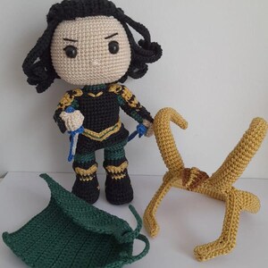 K&ouml;nnte beinhalten: Geh&auml;keltes Pl&uuml;schtier des Marvel-Charakters Loki mit schwarzen Haaren, gr&uuml;ner und goldener Kleidung sowie einer separaten geh&auml;kelten gr&uuml;nen Kapuze und goldenen H&ouml;rnern.