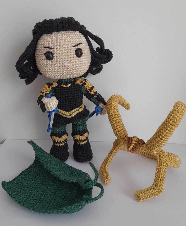 K&ouml;nnte beinhalten: Geh&auml;keltes Pl&uuml;schtier des Marvel-Charakters Loki mit schwarzen Haaren, gr&uuml;ner und goldener Kleidung sowie einer separaten geh&auml;kelten gr&uuml;nen Kapuze und goldenen H&ouml;rnern.