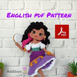 Puede incluir: Patrón de crochet para una muñeca con cabello oscuro, una falda morada y una blusa blanca. La muñeca sostiene un pandero. El patrón está disponible en formato PDF. El texto "ENGLISH PDF PATTERN" está en la parte superior de la imagen. El texto "Additoy" está en la parte inferior de la imagen.