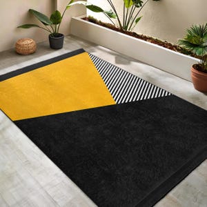 May include: A black and yellow geometric area rug with a black and white striped pattern. The rug has a modern design and is perfect for adding a touch of style to any room.