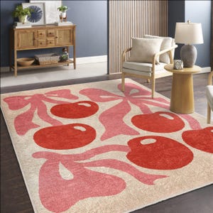 May include: A cream-coloured rug with a pink and red cherry design. The cherries are stylised and have a retro feel. The rug is perfect for adding a touch of whimsy to any room.