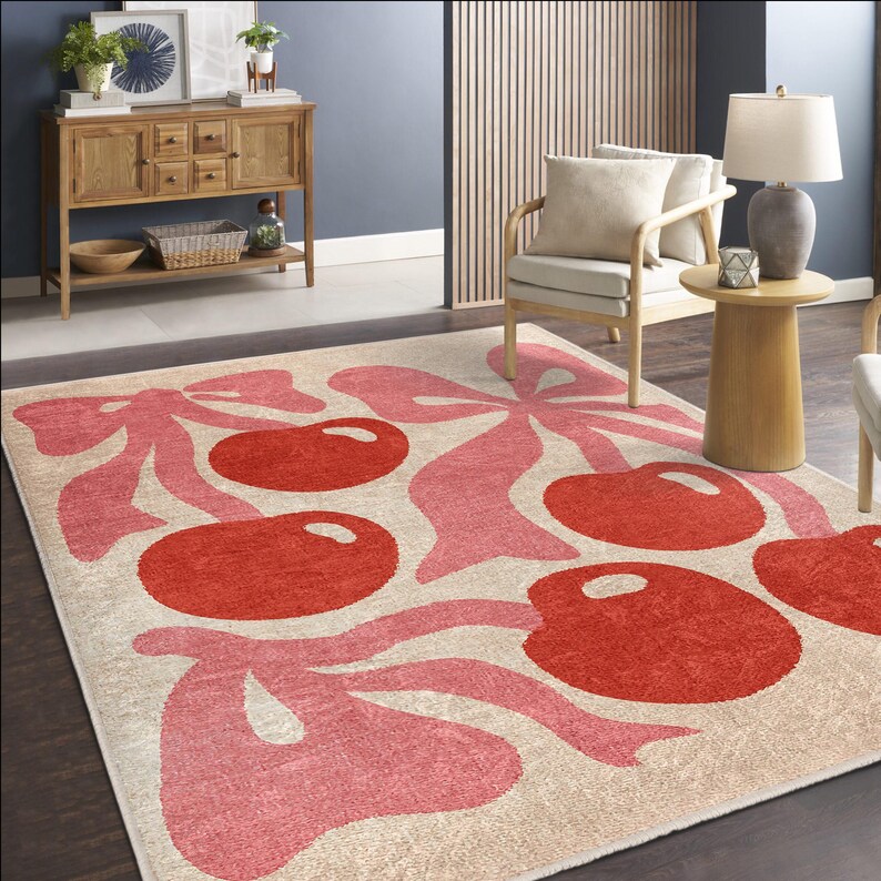 May include: A cream-coloured rug with a pink and red cherry design. The cherries are stylised and have a retro feel. The rug is perfect for adding a touch of whimsy to any room.