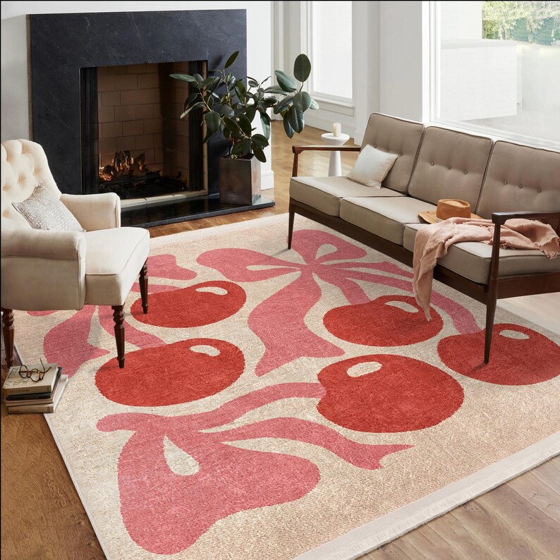 May include: A pink and cream area rug with a cherry motif. The rug features a stylised design of cherries and leaves in a repeating pattern.