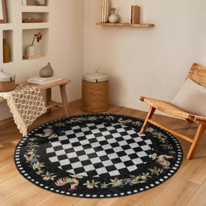 May include: A black and white checkered round rug with a black border featuring a floral and rooster design. The rug is in a room with a wooden chair and a wooden table.