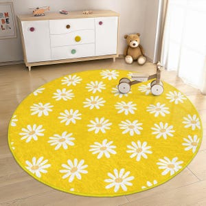 May include: A yellow round play mat with a white daisy pattern. The mat is on a light wood floor.