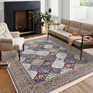 Può includere: Un grande tappeto con un motivo intricato, con uno sfondo crema e un design centrale che presenta una miscela di colori blu, rosso e verde. Il tappeto ha un bordo con un motivo floreale in tonalità marrone e dorate.