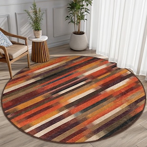 May include: A round area rug with a colorful striped pattern in shades of brown, orange, red, and cream. The rug has a brown border.
