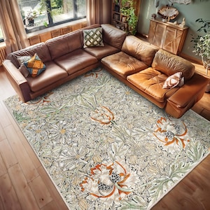 Op de afbeelding: Een crèmekleurig tapijt met een bloemenpatroon in tinten groen, bruin en oranje. Het tapijt ligt op een houten vloer in een woonkamer.