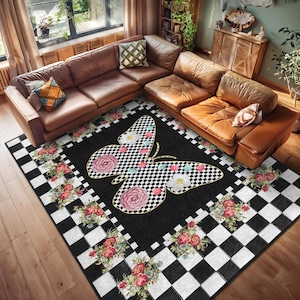 May include: A black and white checkered rug with a floral border and a large butterfly in the center. The butterfly has black and white checkered wings with pink and white flowers.
