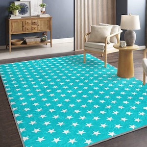 Puede incluir: Una alfombra azul turquesa con un patrón de estrellas blancas. La alfombra está sobre un suelo de madera en un salón.